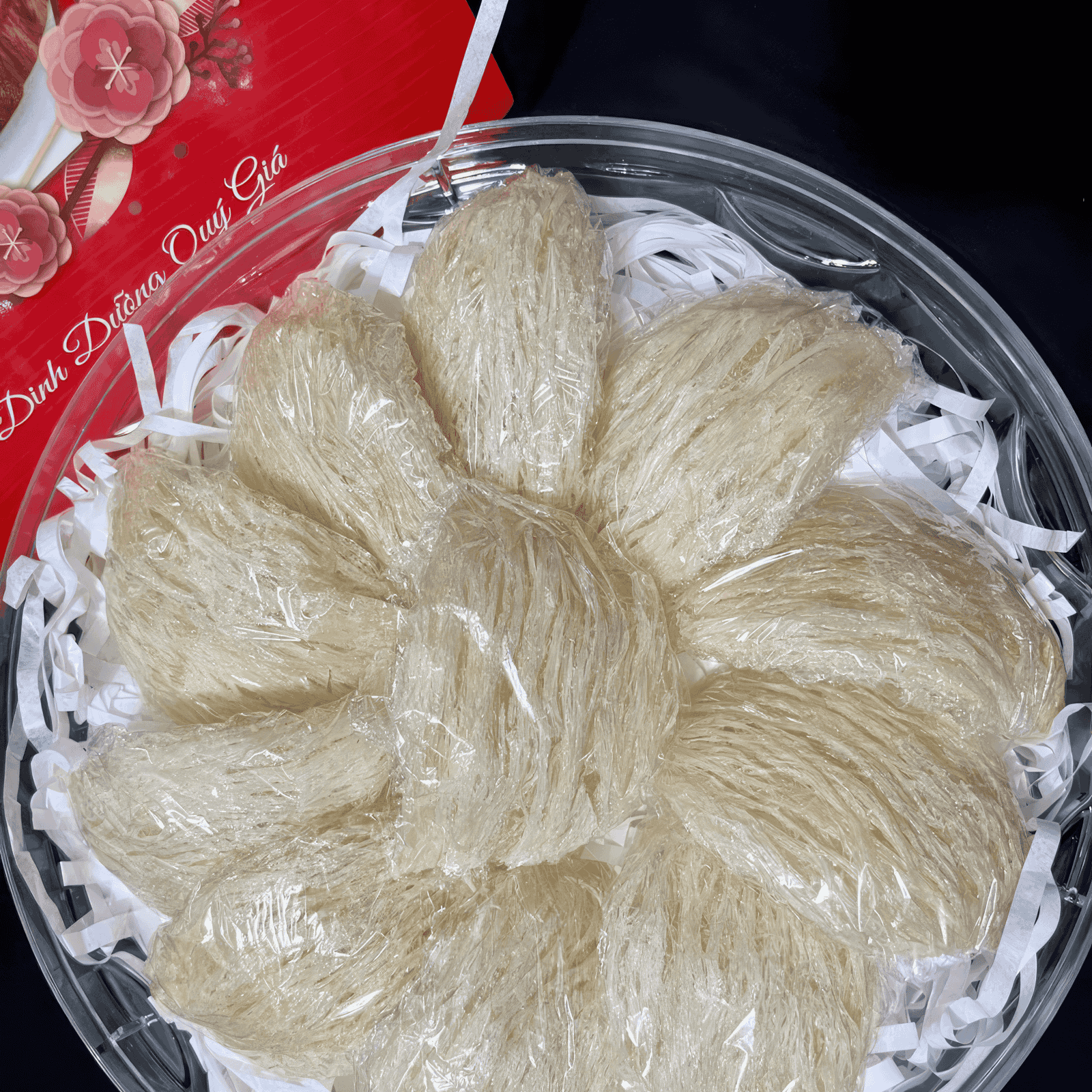Picture of Yến Tinh Chế laying in a basket next to a card with pink flowers