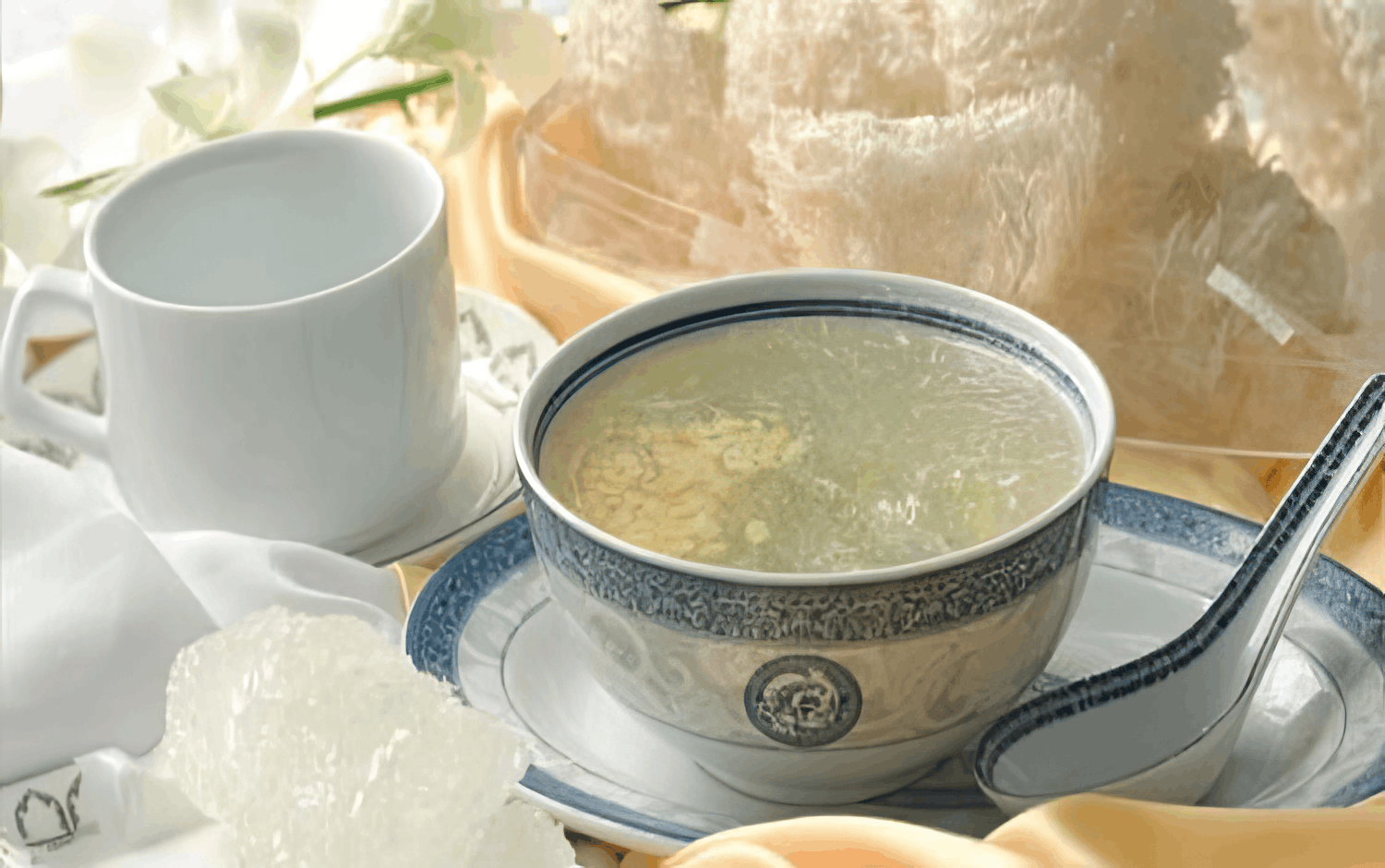 Small bowl of bird nest soup, coffee mug and cleaned shallow bird nest sitting on a plate